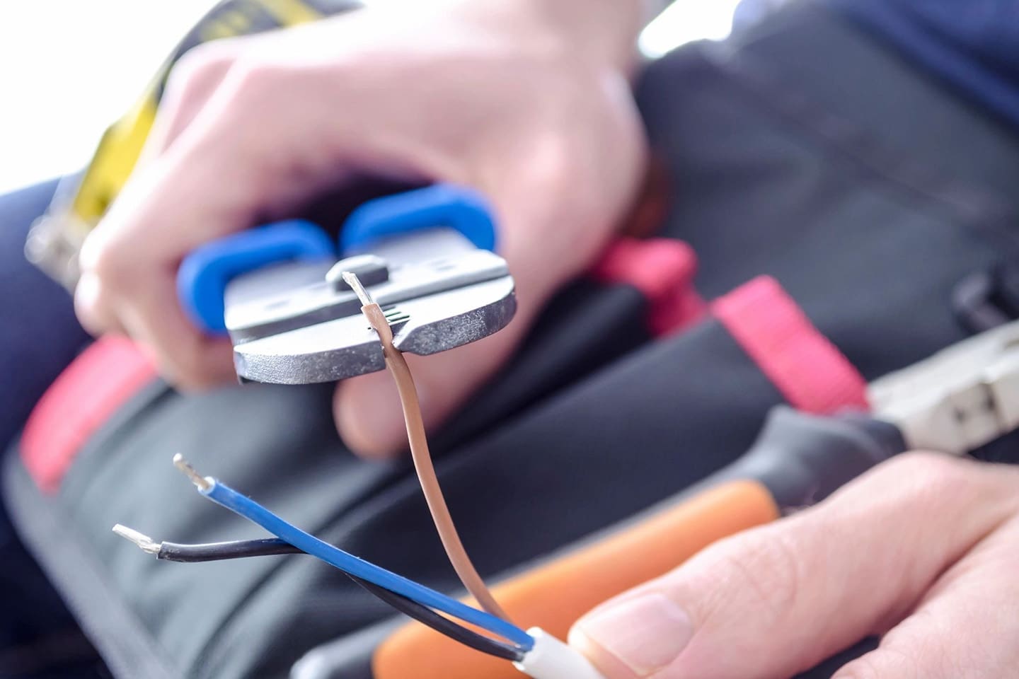 A person is holding wires and tools in their hands.