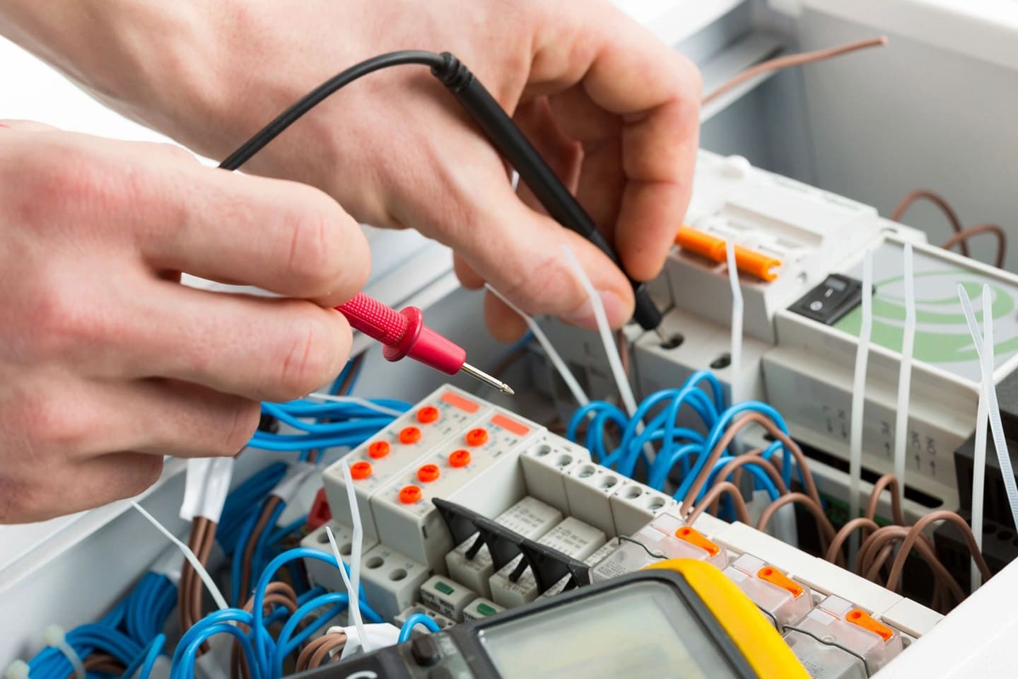 A person working on electrical equipment with wires and cables.